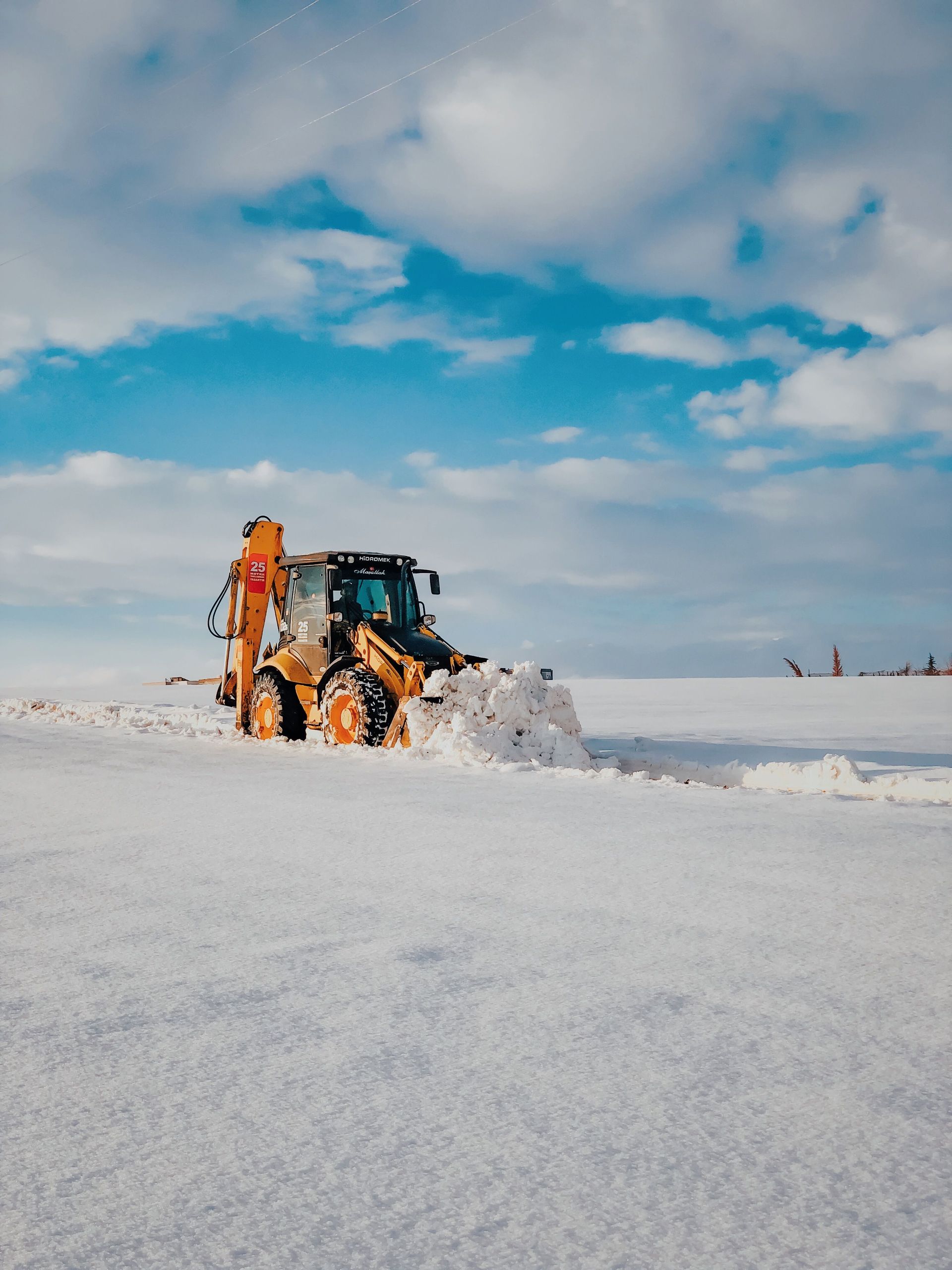 A bulldozer efficiently clearing snow in a winter landscape with a bright blue sky.